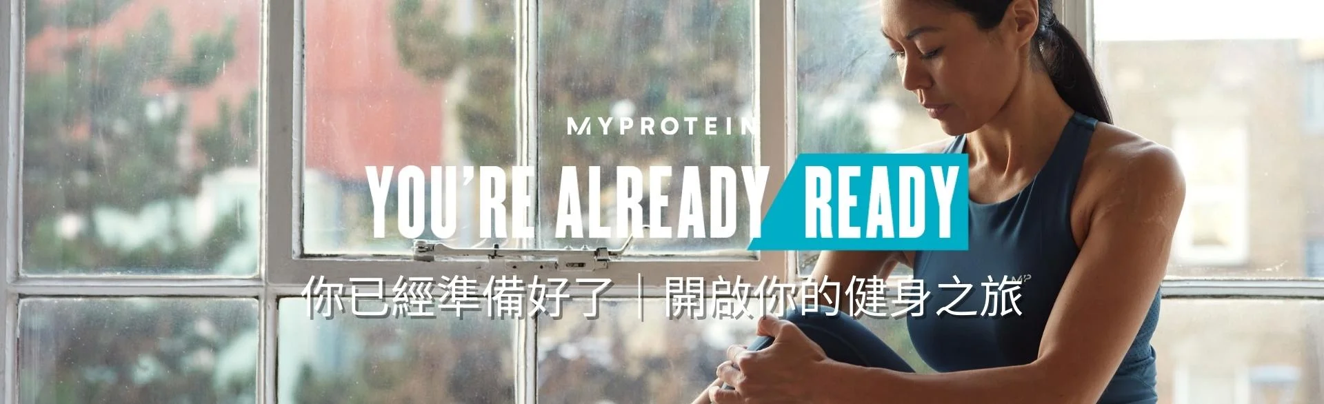 A woman wearing MP gym clothing sat on a window ledge stretching with the text 'You're Already Ready - MYPROTEIN' overlaying the image.